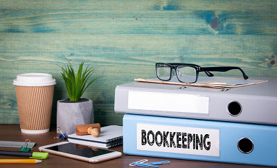 binders labeled bookkeeping on top of desk